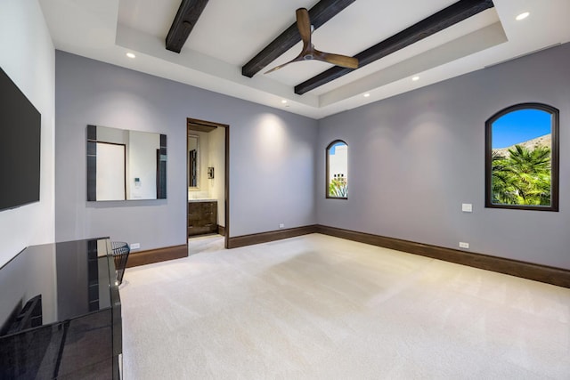 empty room with carpet flooring, a raised ceiling, ceiling fan, and beam ceiling