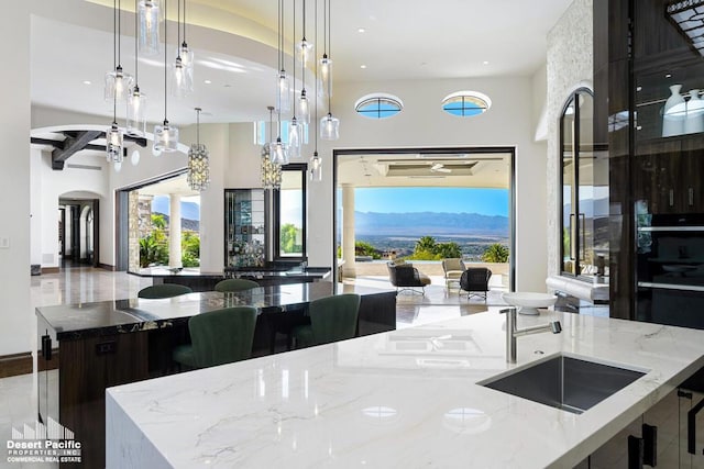 kitchen with hanging light fixtures, a mountain view, light stone countertops, and plenty of natural light