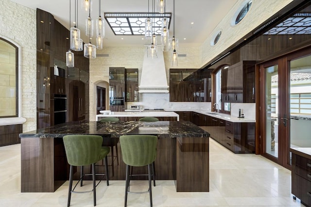 kitchen with dark brown cabinets, decorative light fixtures, a large island, and dark stone countertops