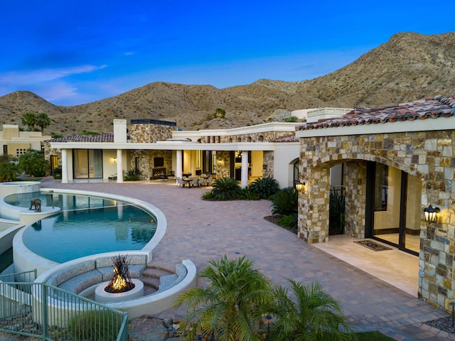 view of swimming pool with a fire pit, a mountain view, and a patio area