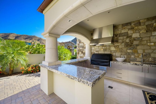 view of patio / terrace with area for grilling, a mountain view, a bar, and grilling area