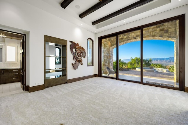 carpeted empty room featuring a mountain view and beam ceiling