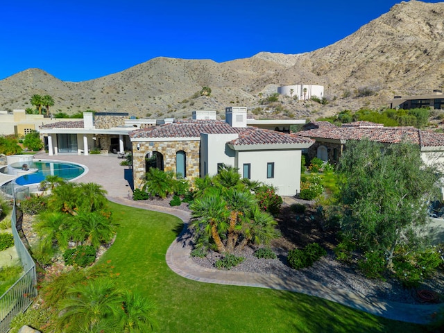 rear view of property featuring a mountain view, a patio area, a fenced in pool, and a yard