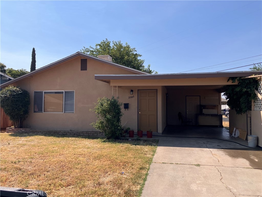 ranch-style home featuring a carport and a front yard