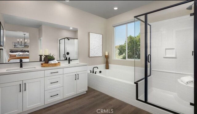 bathroom with wood-type flooring, a chandelier, independent shower and bath, and vanity