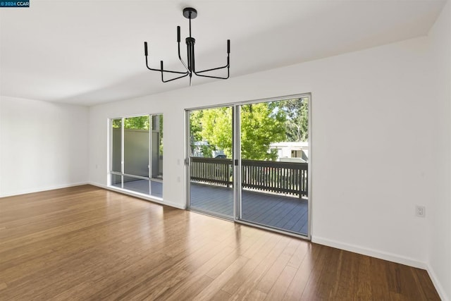 unfurnished dining area with an inviting chandelier and hardwood / wood-style floors