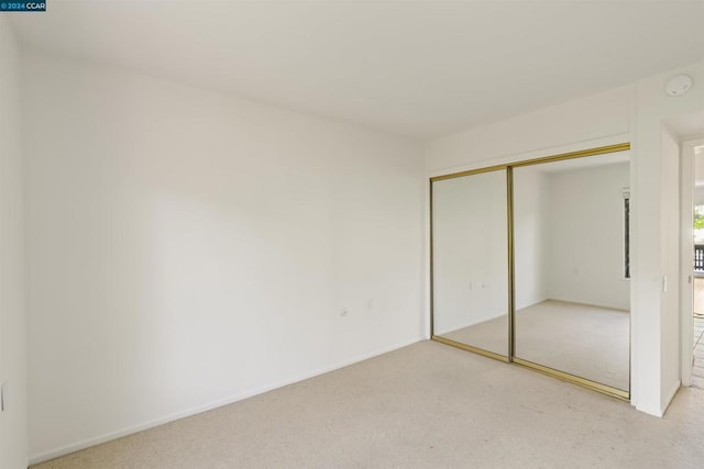 unfurnished bedroom with a closet and light carpet