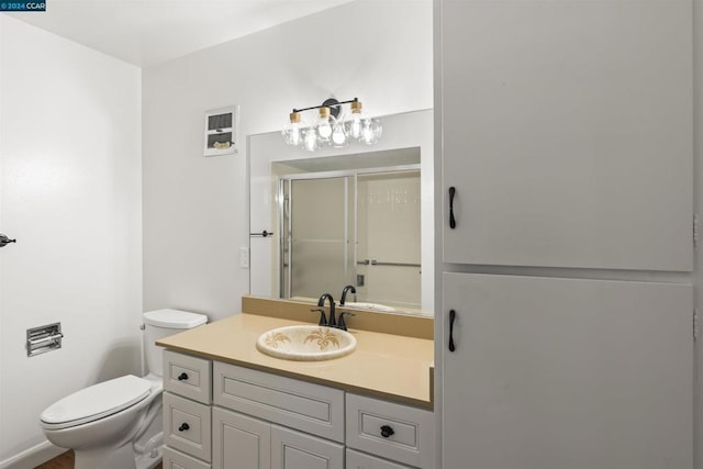 bathroom with an enclosed shower, vanity, and toilet