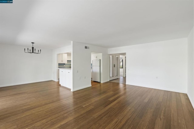 unfurnished living room featuring a notable chandelier and dark wood-type flooring