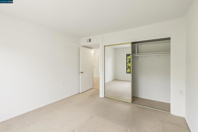 unfurnished bedroom with light colored carpet and a closet