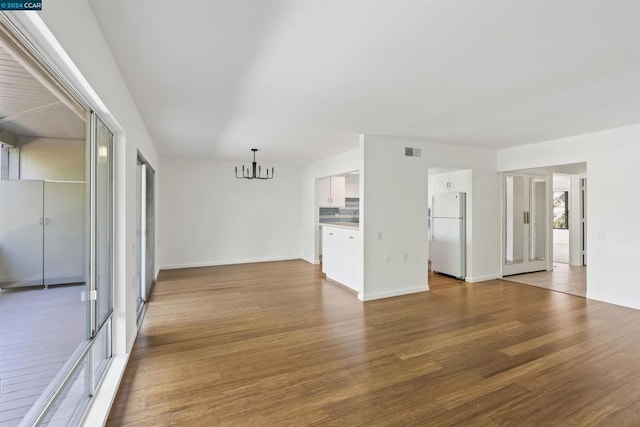 unfurnished living room featuring an inviting chandelier and hardwood / wood-style flooring