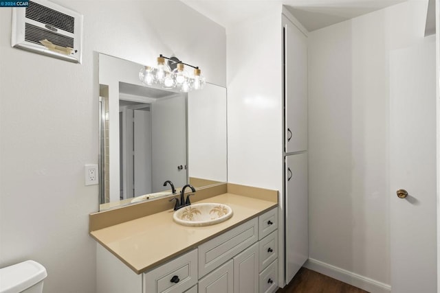 bathroom featuring toilet, vanity, and an AC wall unit