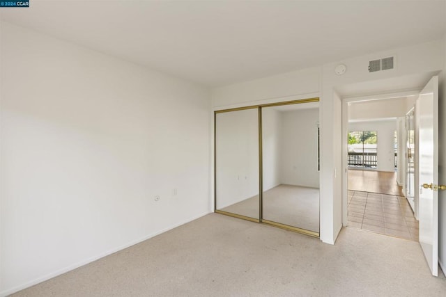 unfurnished bedroom featuring light colored carpet and a closet