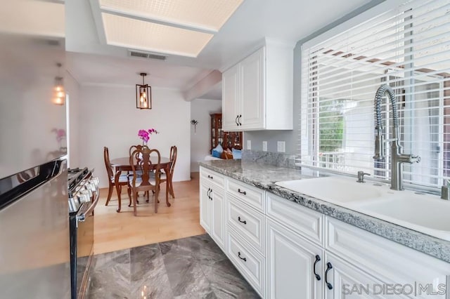 kitchen with hardwood / wood-style flooring, sink, pendant lighting, white cabinetry, and appliances with stainless steel finishes