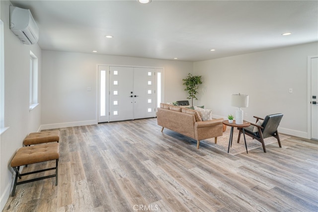 living room with a wall mounted AC and light hardwood / wood-style flooring