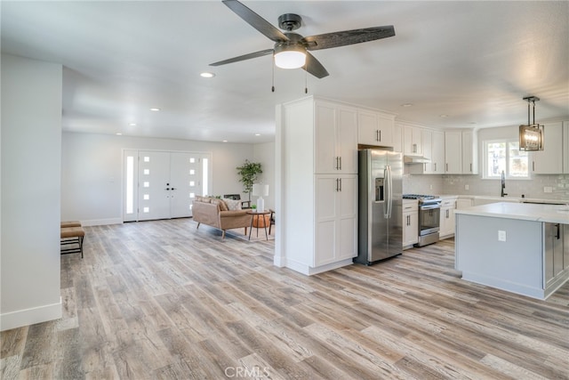 kitchen featuring stainless steel appliances, white cabinets, ceiling fan, and light wood-type flooring