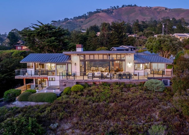 back house at dusk featuring outdoor lounge area, a mountain view, and a patio