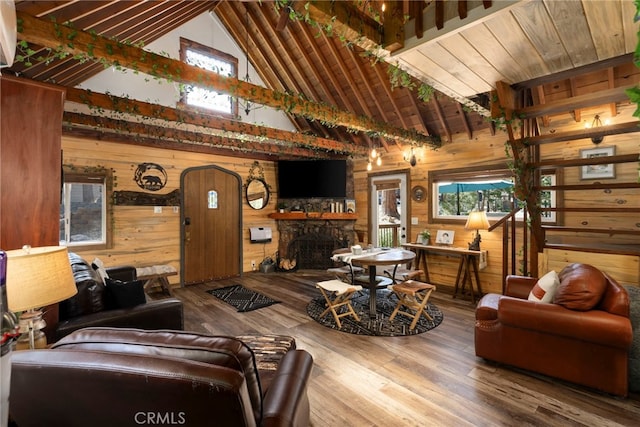 living room featuring a fireplace, wooden walls, hardwood / wood-style floors, and high vaulted ceiling