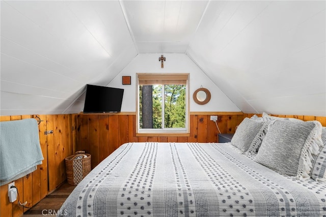 bedroom with lofted ceiling, wood walls, and dark wood-type flooring