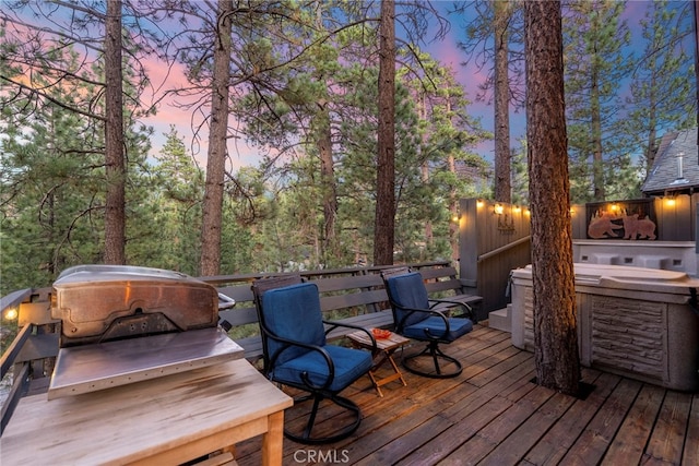 deck at dusk featuring a hot tub