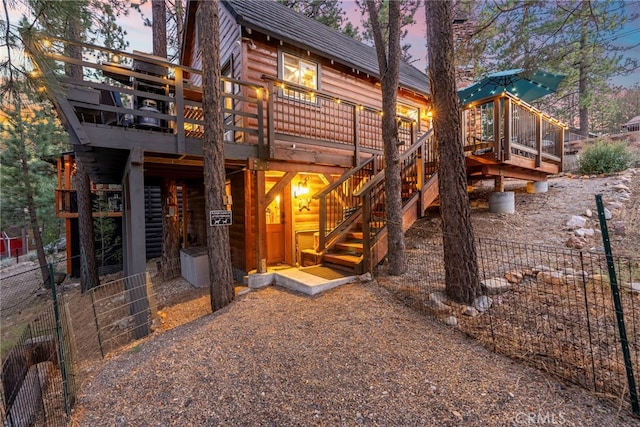 back house at dusk with a wooden deck