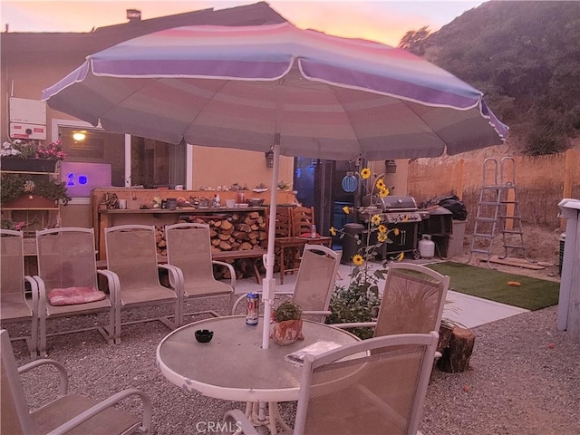 patio terrace at dusk featuring a mountain view and area for grilling