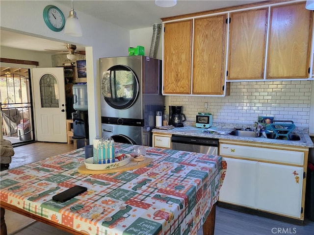 kitchen with decorative backsplash, ceiling fan, sink, stacked washer / dryer, and dishwasher