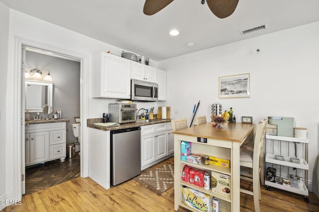 kitchen featuring appliances with stainless steel finishes, light wood-type flooring, ceiling fan, sink, and white cabinetry