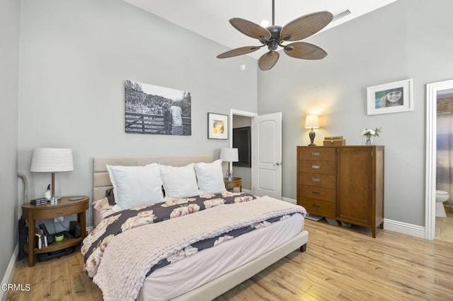 bedroom featuring ensuite bath, ceiling fan, a towering ceiling, and light hardwood / wood-style floors