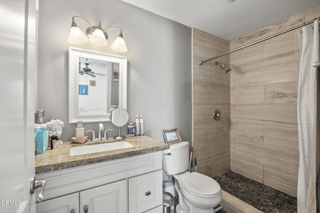 bathroom featuring a shower with curtain, ceiling fan, vanity, and toilet