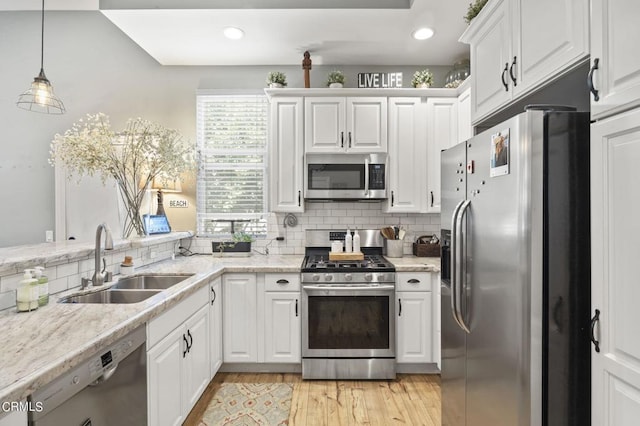 kitchen with appliances with stainless steel finishes, backsplash, sink, pendant lighting, and white cabinetry