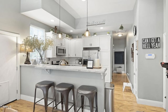 kitchen featuring light stone countertops, white cabinetry, tasteful backsplash, pendant lighting, and appliances with stainless steel finishes