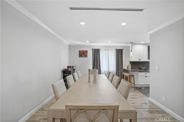 dining room with light hardwood / wood-style floors and ornamental molding