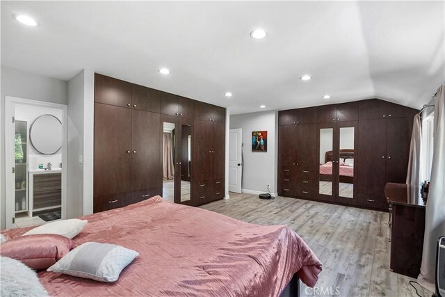 bedroom featuring light hardwood / wood-style floors, french doors, connected bathroom, and vaulted ceiling