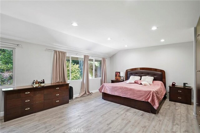 bedroom featuring vaulted ceiling, light hardwood / wood-style flooring, and multiple windows