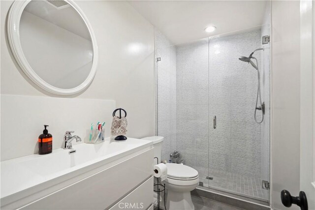 bathroom featuring vanity, a shower with shower door, and toilet