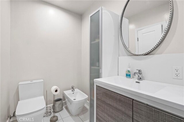 bathroom featuring toilet, vanity, tile patterned floors, and a bidet