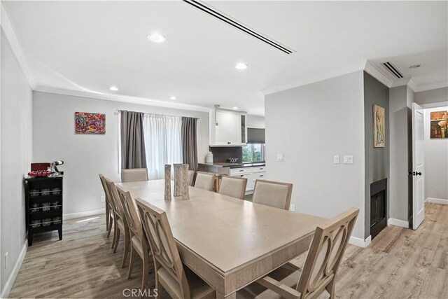 dining room featuring light wood-type flooring and crown molding