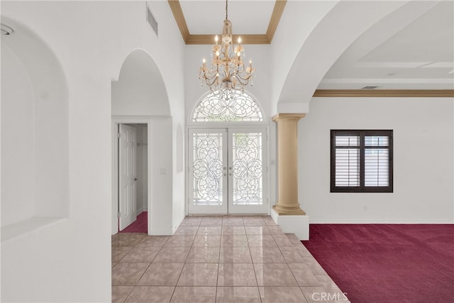 foyer entrance with french doors, beamed ceiling, a notable chandelier, ornamental molding, and light colored carpet