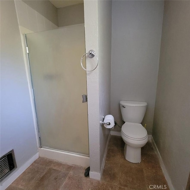 bathroom featuring a shower with shower door and toilet