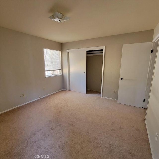 unfurnished bedroom featuring light carpet and a closet