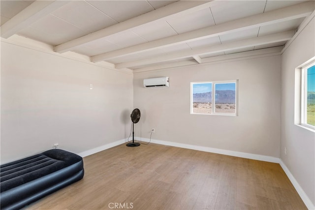 interior space with a wall mounted AC, beam ceiling, hardwood / wood-style flooring, and a healthy amount of sunlight