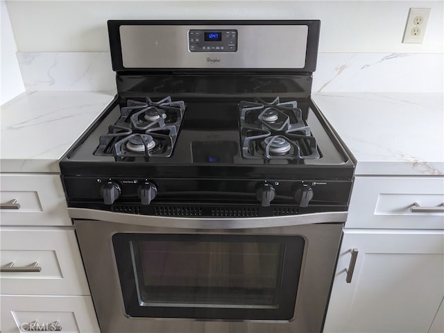 room details featuring light stone counters, white cabinetry, and stainless steel range with gas stovetop