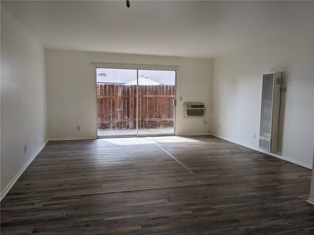 unfurnished room featuring a wall mounted AC and dark wood-type flooring