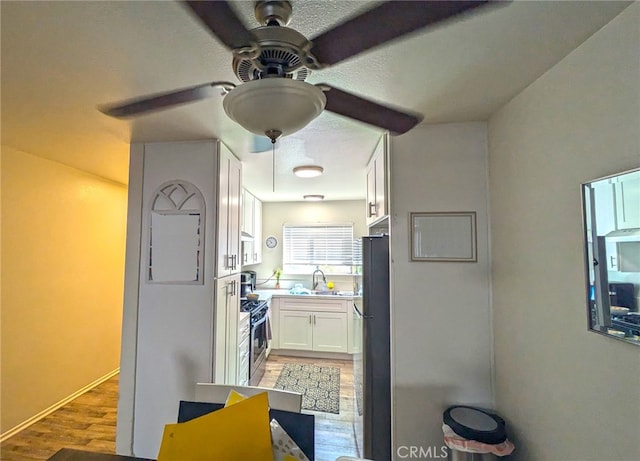 kitchen with white cabinetry, electric stove, wood-type flooring, ceiling fan, and sink