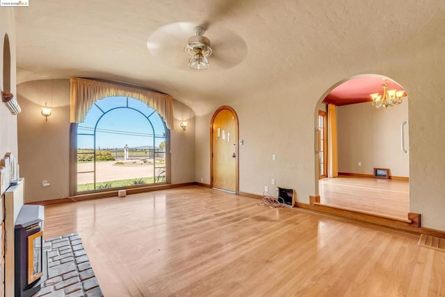 unfurnished living room featuring ceiling fan with notable chandelier, lofted ceiling, and hardwood / wood-style floors