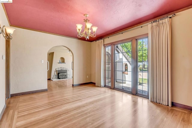 empty room with an inviting chandelier, light wood-type flooring, and ornamental molding