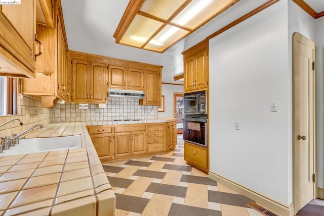 kitchen featuring ornamental molding, sink, tile counters, decorative backsplash, and a healthy amount of sunlight