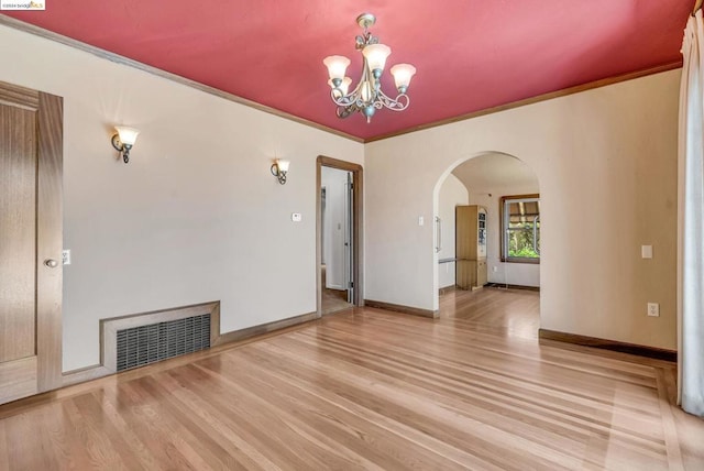 unfurnished living room featuring ornamental molding, light hardwood / wood-style floors, and an inviting chandelier