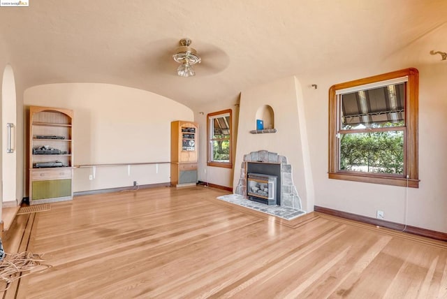 unfurnished living room featuring hardwood / wood-style flooring, vaulted ceiling, ceiling fan, and a wealth of natural light